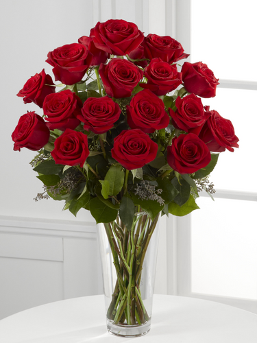 Eighteen red roses with greenery arranged in a tall clear glass vase