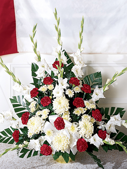 Red and white sympathy arrangement with carnations, gladiolus, chrysanthemums and greenery