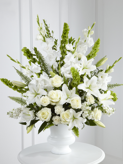 Large white sympathy arrangement with lilies, roses, gladiolus and greenery