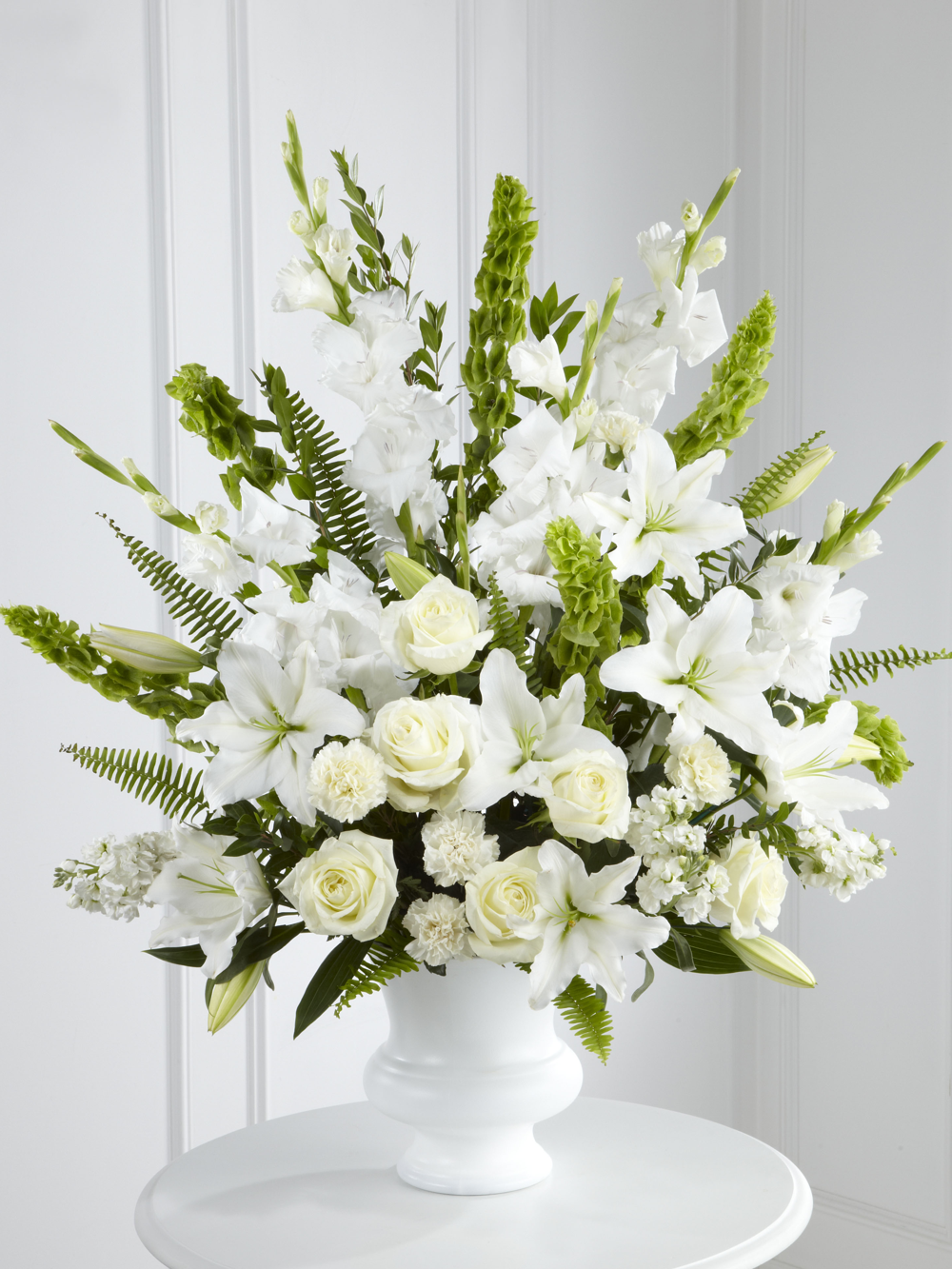 Large white sympathy arrangement with lilies, roses, gladiolus and greenery