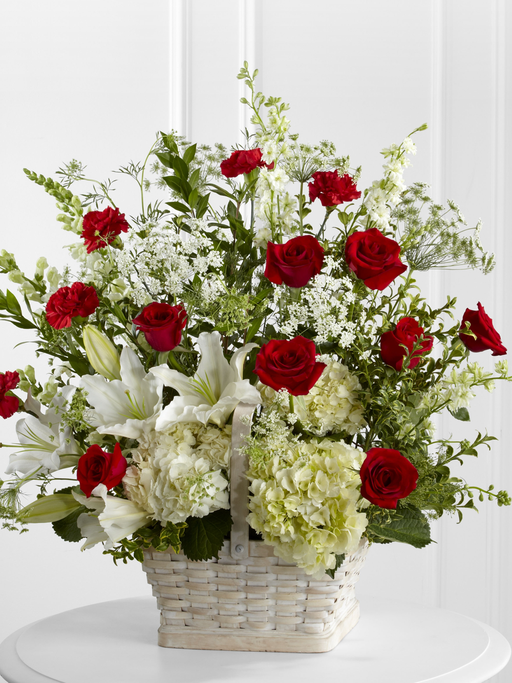 Large red and white funeral basket with roses, lilies, hydrangea and greenery